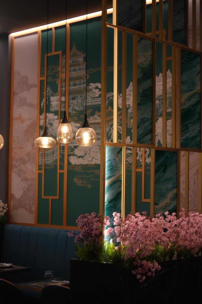 Interior del restaurante con mural verde, flores y lámparas